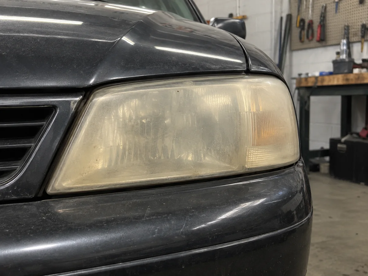 Yellowed, hazy outer lens on an older car headlight seen from the front
