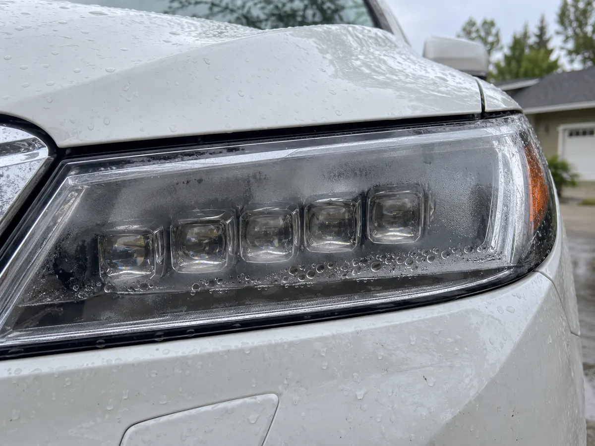 Water droplets along the bottom of an Acura MDX Jewel Eye LED headlight lens
