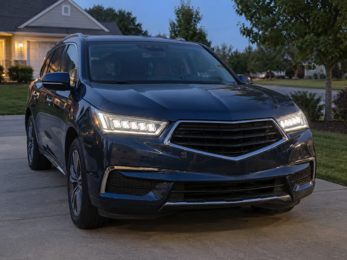Front of an Acura MDX SUV at dusk with both Jewel Eye LED headlights lit