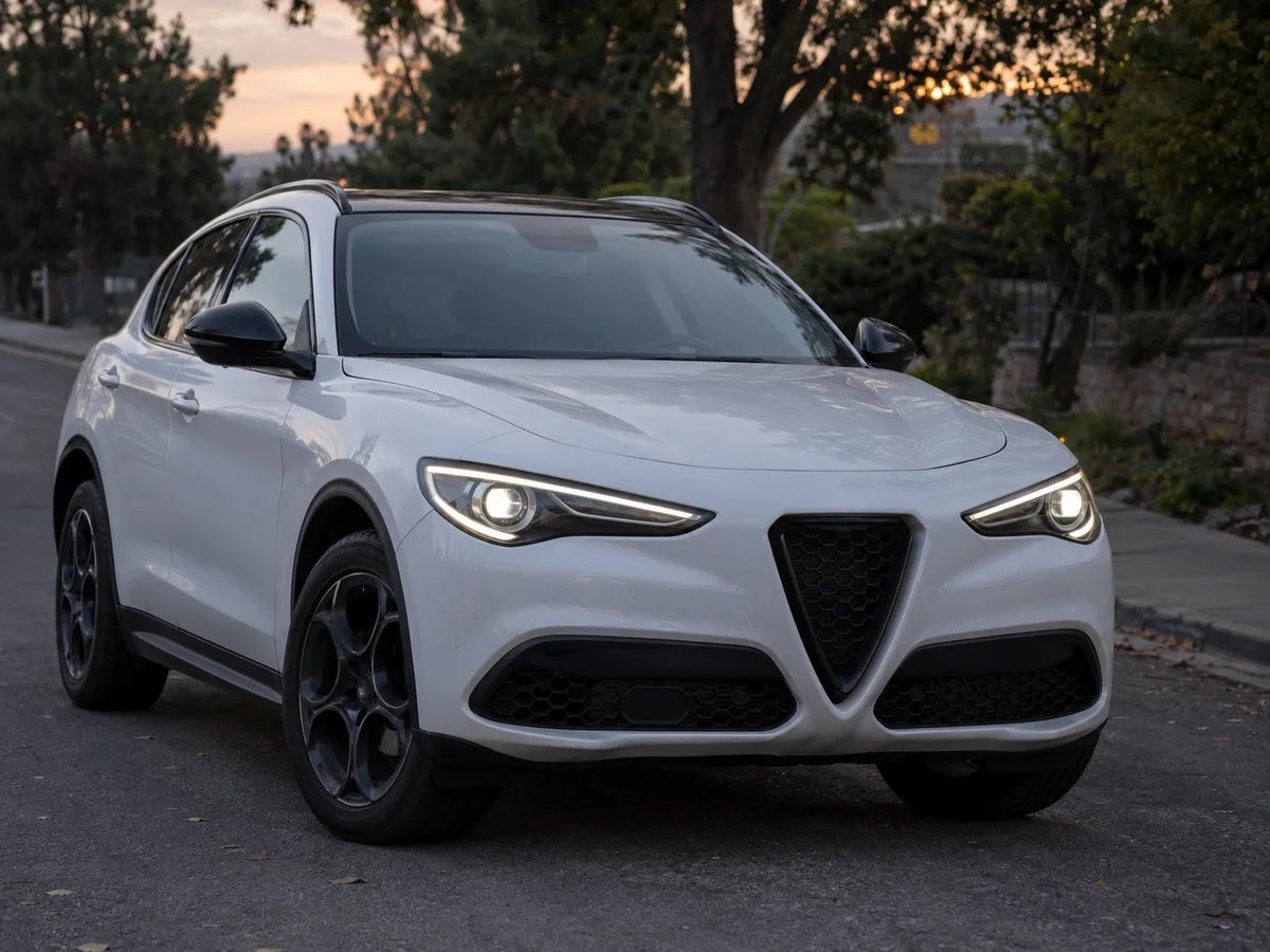 Front of an Alfa Romeo Stelvio at dusk with both headlights lit