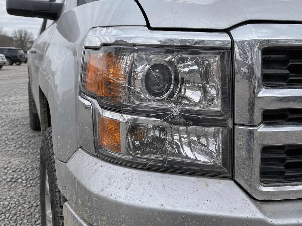 Passenger side headlight of a Chevy Silverado with spider cracks across the lens