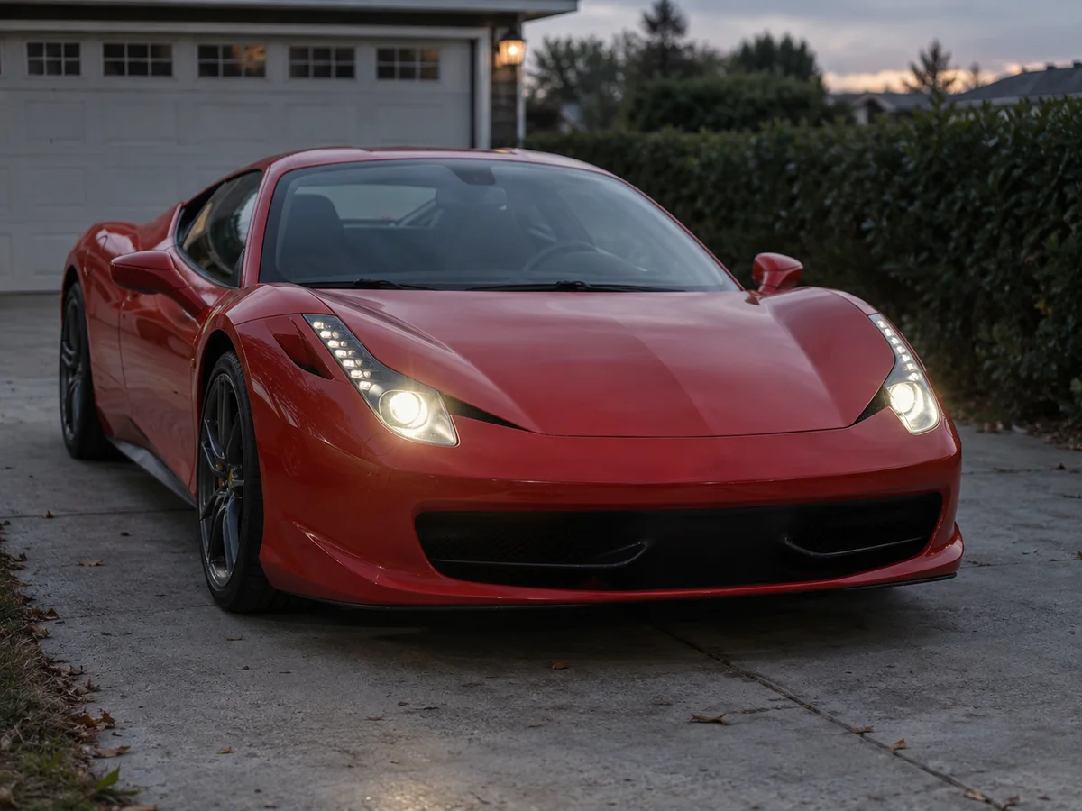 Front of a Ferrari 458 with both headlights on at dusk