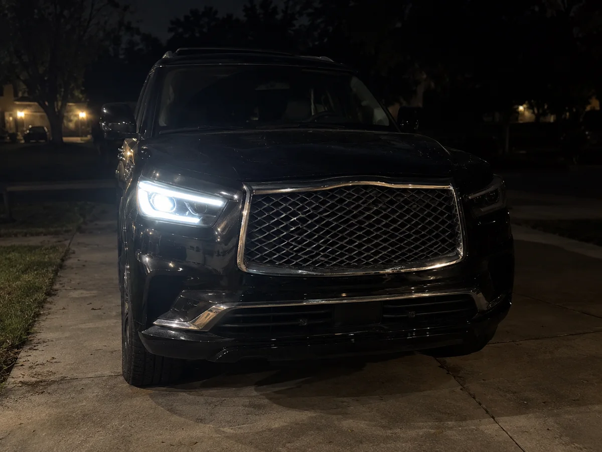 Front of an Infiniti QX80 at night with one LED headlight lit and the other dark
